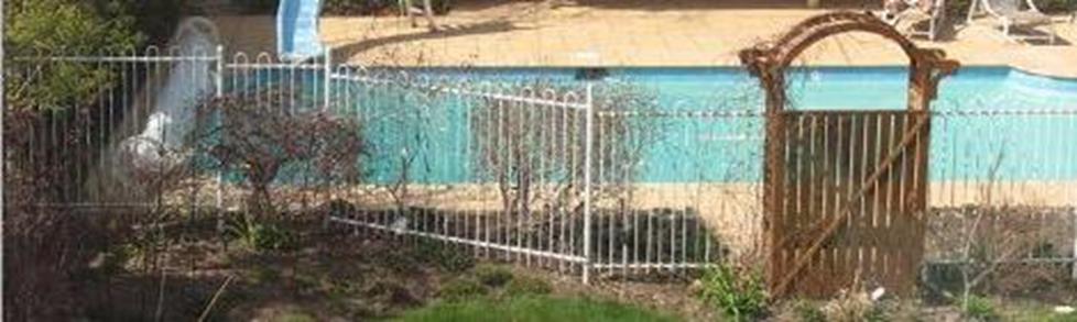 Aerial view of a swimmingpool behind a white fence.